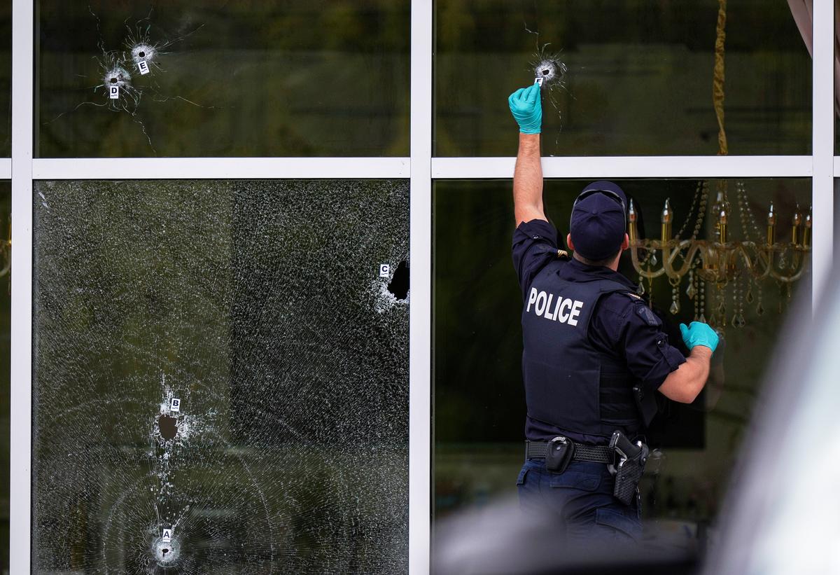 एक रॉयल कैनेडियन माउंटेड पुलिस (आरसीएमपी) के अधिकारी सरे, ब्रिटिश कोलंबिया, गुरुवार, अगस्त में एक कैफे की खिड़कियों में बुलेट छेद के बगल में बुलेट छेद के बगल में सबूत मार्कर रखते हैं। 7, 2025, जैसा कि कपिल शर्मा के काप के कैफ के कैफे में एक महीने के भीतर दूसरी बार शॉट के बाद पुलिस की जांच की गई थी।