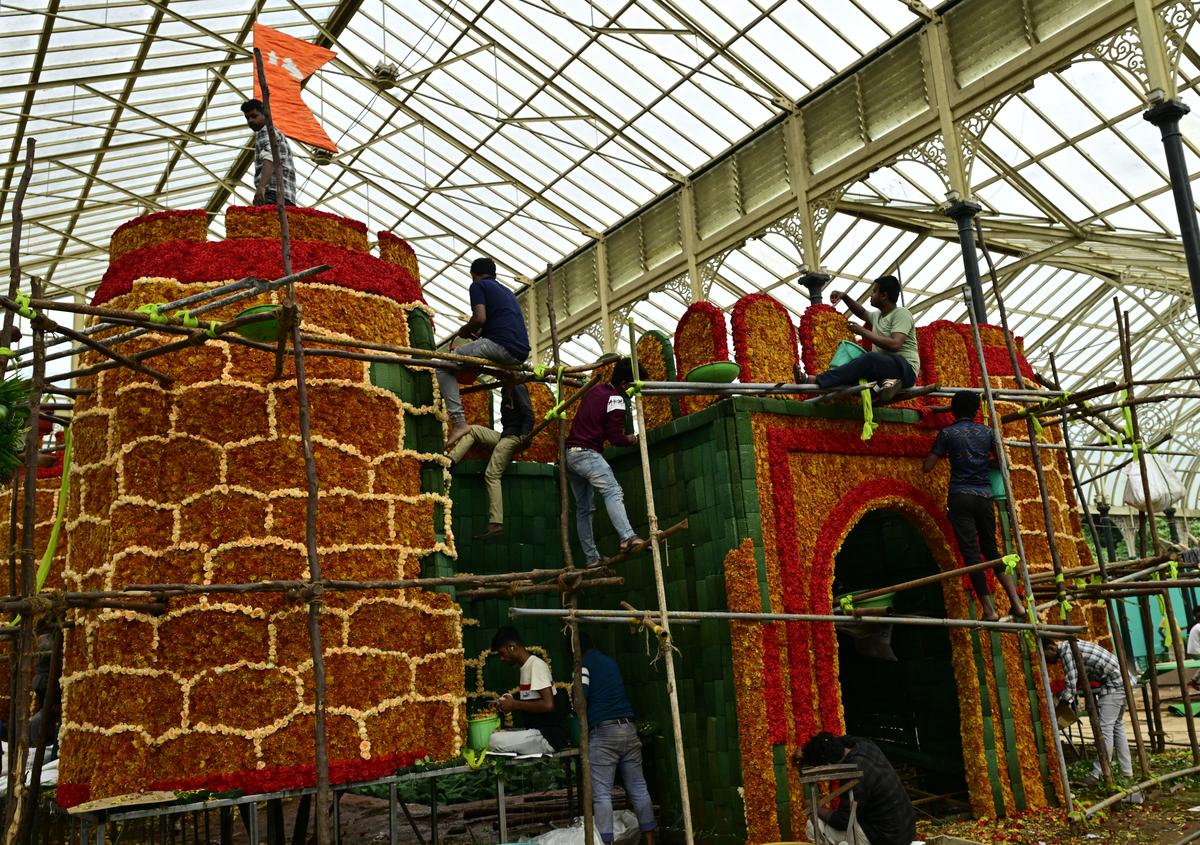 भूरे रंग के डच गुलदाउदी का उपयोग करने वाले श्रमिक, लाल और आड़ू रंग के गुलाब के साथ, 'किले का किला' बनाने के लिए। किले का यह मॉडल बेंगलुरु के लालबाग में इस वर्ष के स्वतंत्रता दिवस फ्लावर शो का केंद्रीय आकर्षण टुकड़ा होगा।