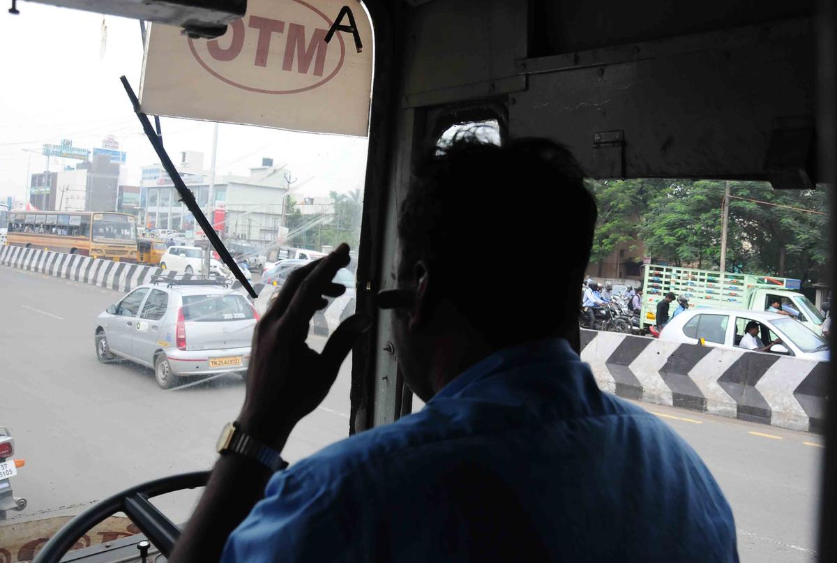 व्यस्त सड़क पर ड्राइविंग करते समय ब्लूटूथ के साथ सेल फोन का उपयोग करने वाला एक बस ड्राइवर।