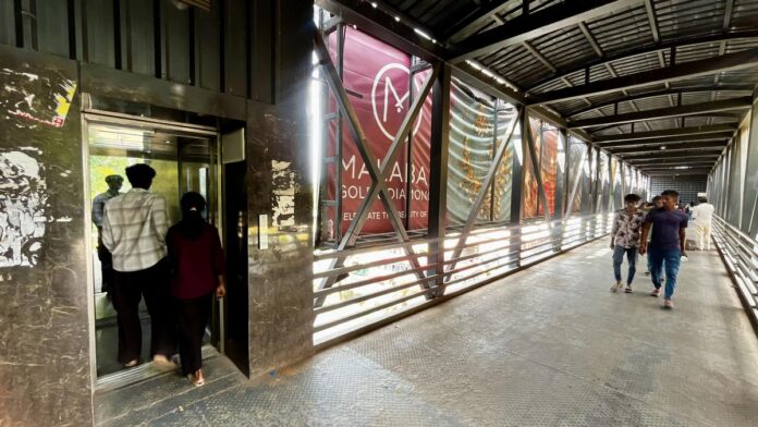 लोग बेंगलुरु में एक लिफ्ट के माध्यम से राजसी में एक मेट्रो स्टेशन के पास पुलों पर पैर का उपयोग करते हैं।