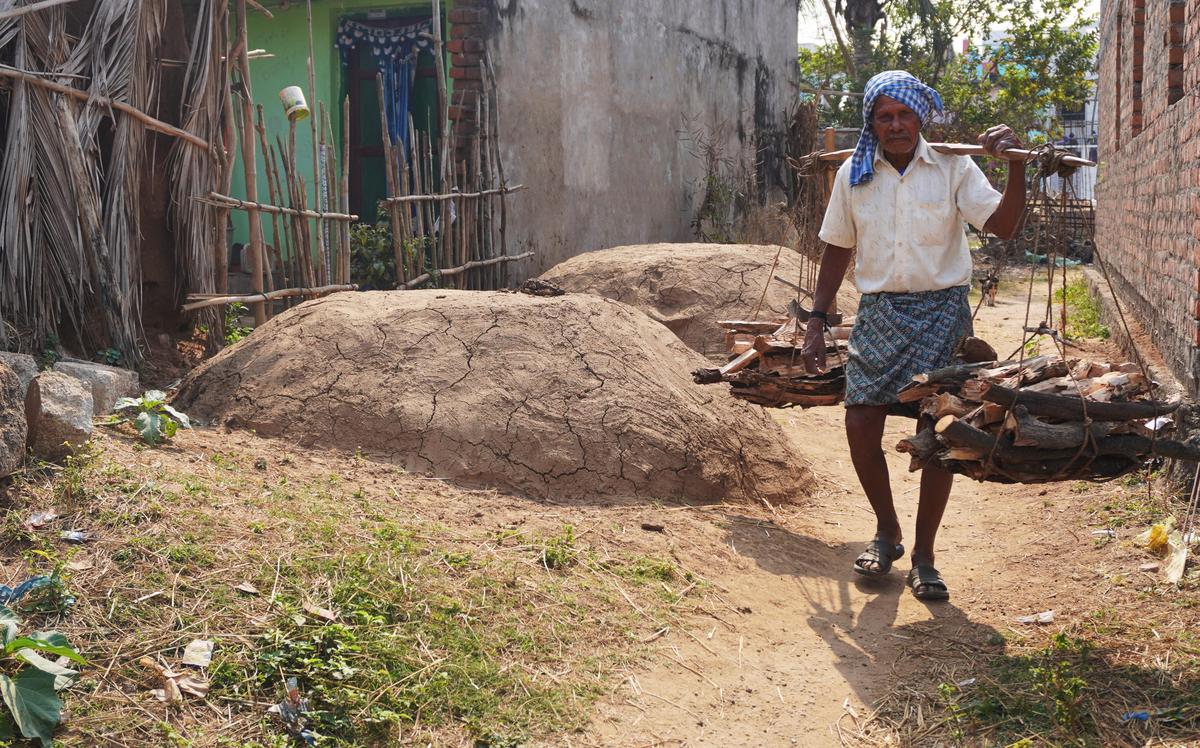 श्रीकाकुलम जिले के कांचिली मंडल के पूर्णा सासनम गांव में एक आदमी लकड़ी लेकर खोनिस के पास से गुजर रहा है।