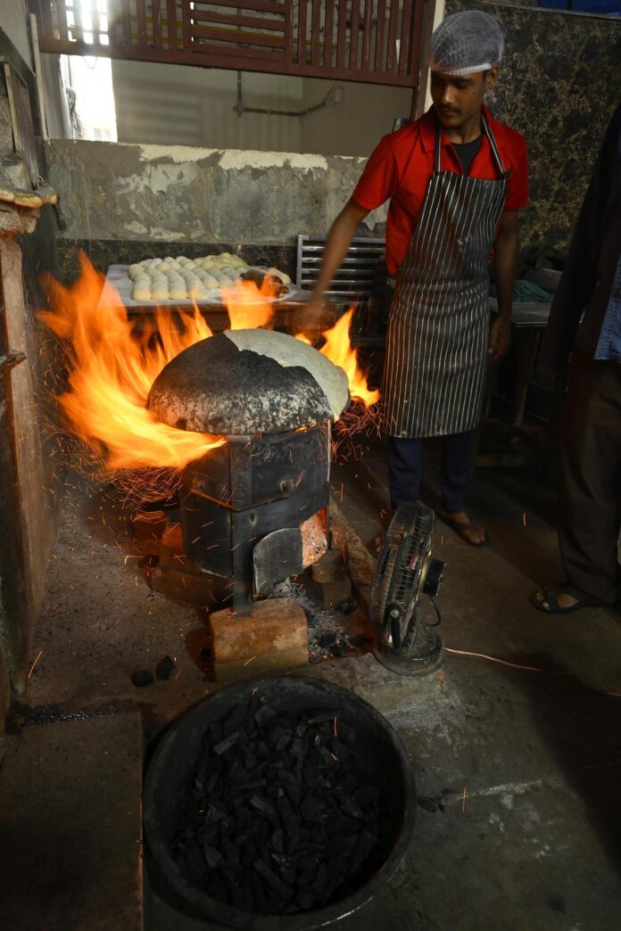 हैदराबाद के मेहदीपट्टनम में एक रेस्तरां में रसोइये एलपीजी की कमी के कारण जलाऊ लकड़ी और कोयले का उपयोग करके बिरयानी तैयार करते हैं। यह संकट पश्चिम एशिया में एक संघर्ष के मद्देनजर आया है जिसने भारत की एलपीजी जीवन रेखा को आपूर्ति करने वाले प्रमुख समुद्री मार्गों को बाधित कर दिया है।